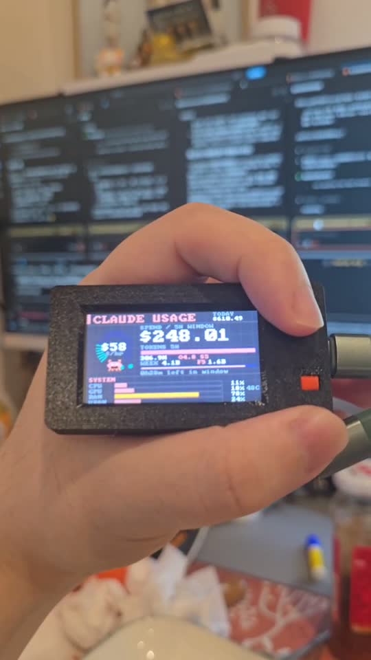 ClawdMiner 就擺在我桌上,背景是我開著 Claude Code 的螢幕
